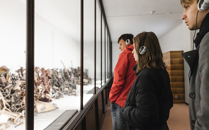 Visitors with audio guides at Auschwitz-Birkenau Memorial and Museum exhibit.