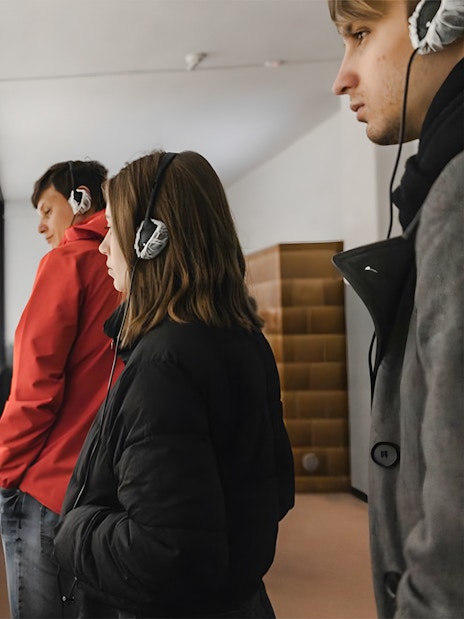 Visitors with audio guides at Auschwitz-Birkenau Memorial and Museum exhibit.