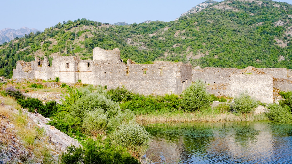 Lesendro Castle ruins by Skadar Lake in Montenegro with lush green hills.