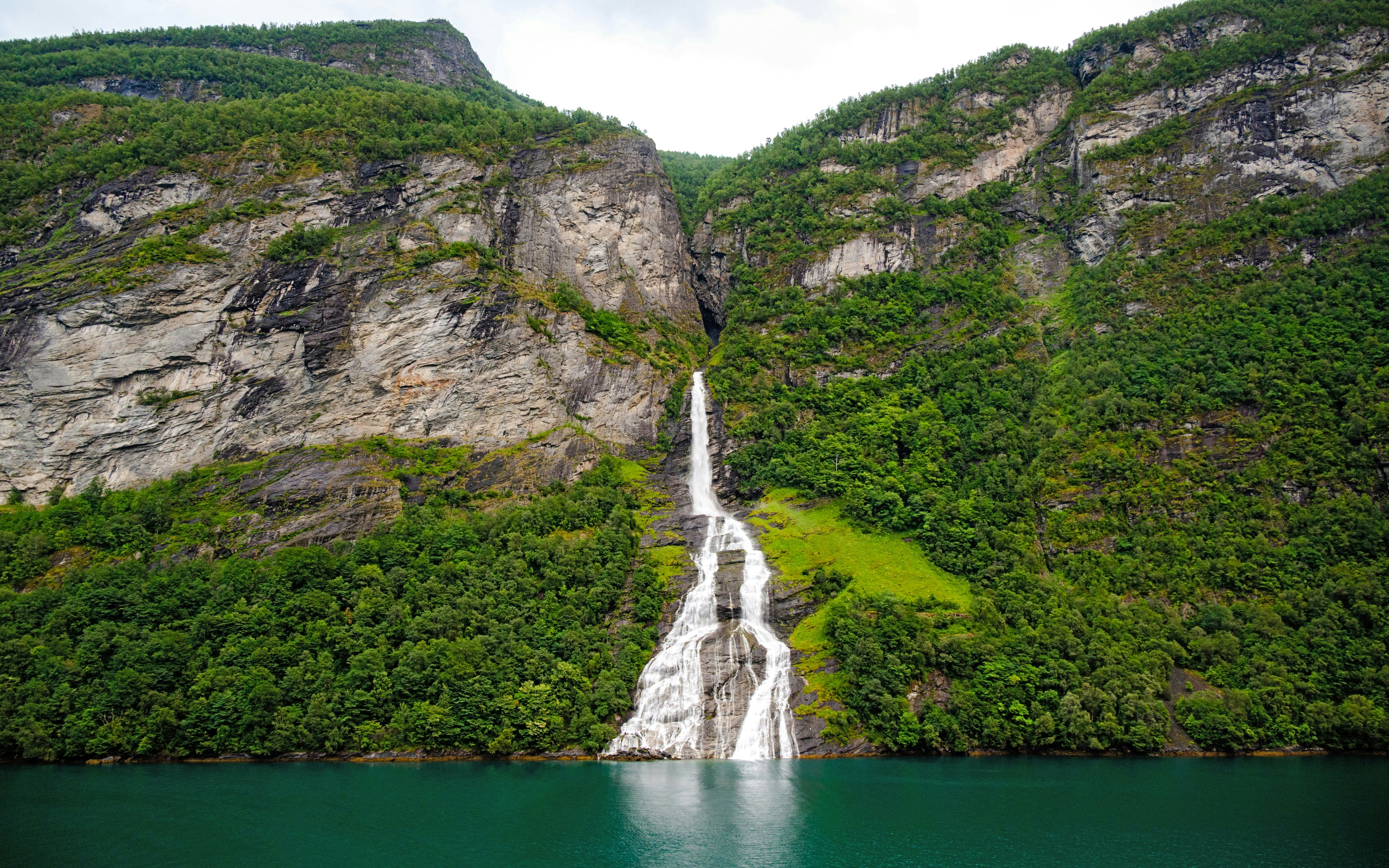 The Suitor waterfall cascading down cliffs into Geiranger fjord, Norway.