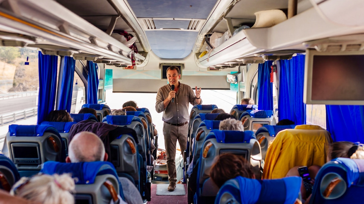 Tour guide speaking to passengers on a bus heading to Mycenae archaeological site, Peloponnese, Greece.