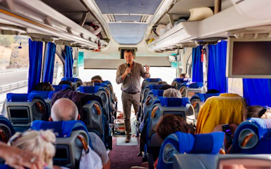 Tour guide speaking to passengers on a bus heading to Mycenae archaeological site, Peloponnese, Greece.