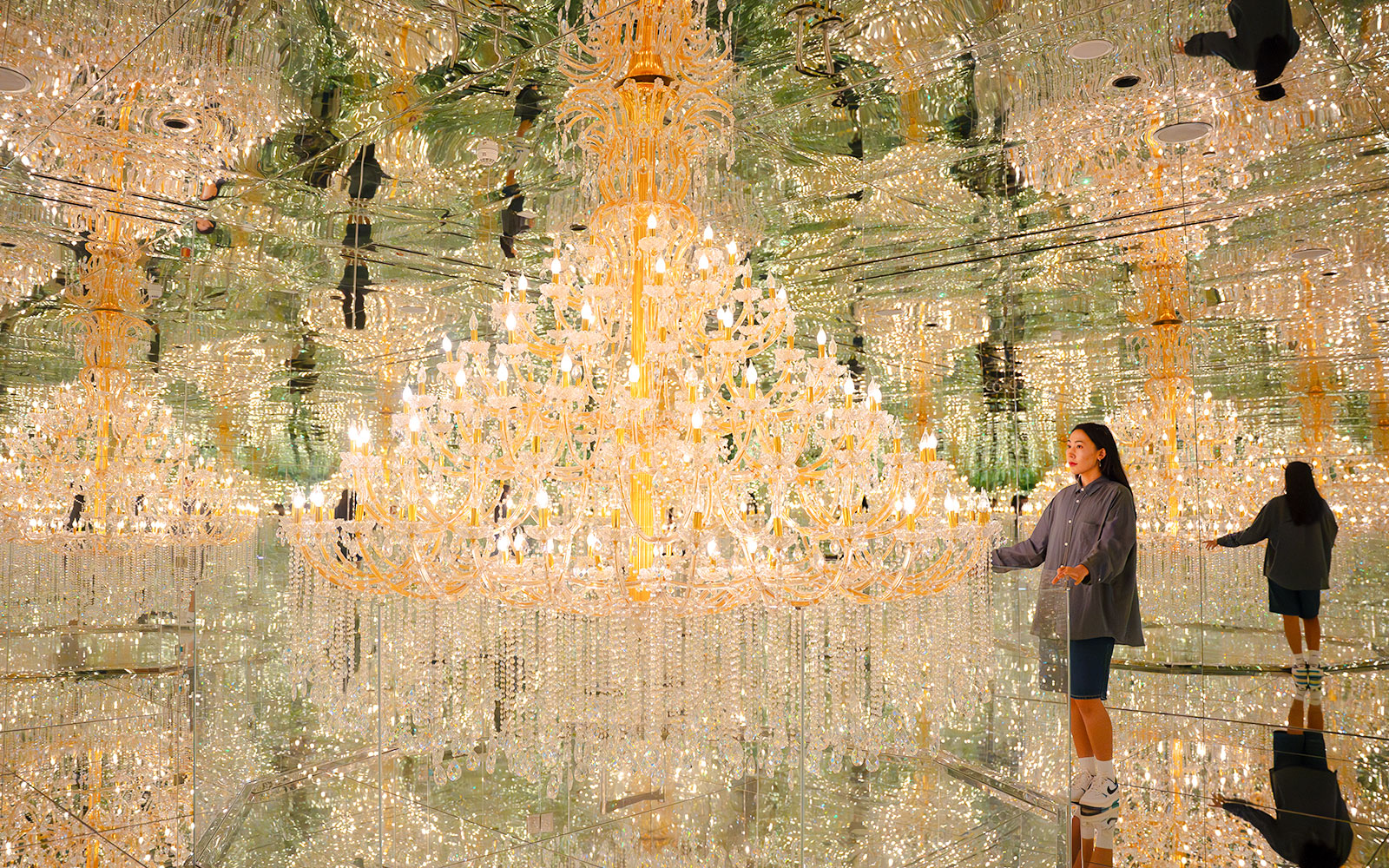 Tourist admiring chandeliers in mirrored room at House of Hype, Dubai.