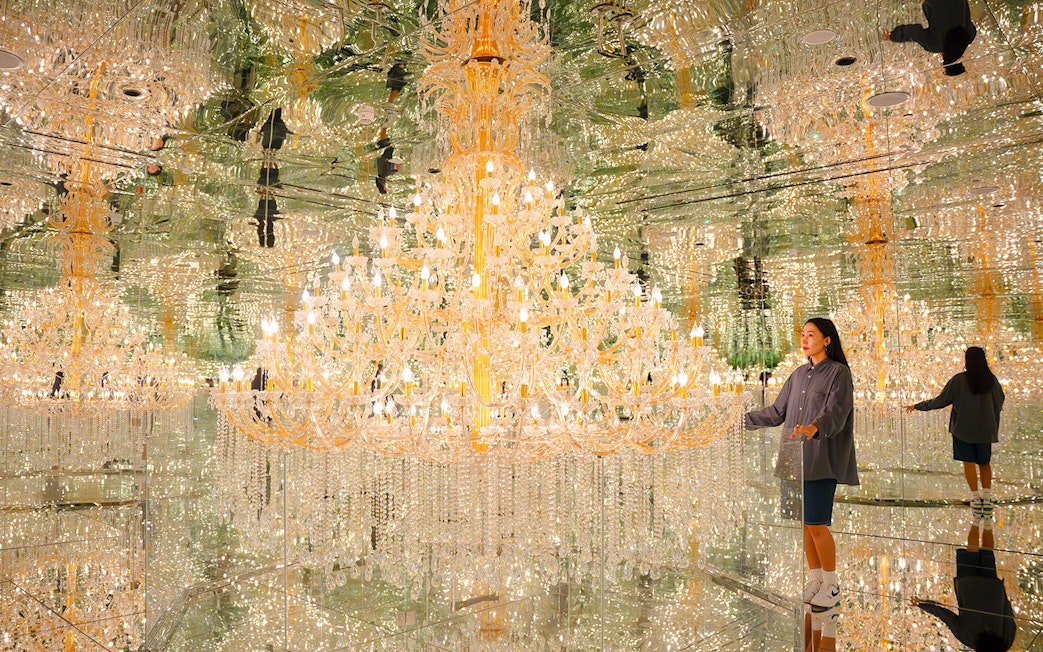 Tourist admiring chandeliers in mirrored room at House of Hype, Dubai.