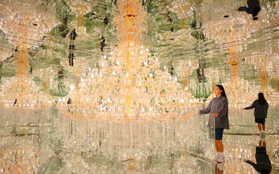 Tourist admiring chandeliers in mirrored room at House of Hype, Dubai.