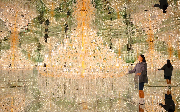 Tourist admiring chandeliers in mirrored room at House of Hype, Dubai.