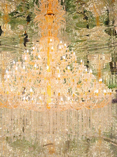 Tourist admiring chandeliers in mirrored room at House of Hype, Dubai.