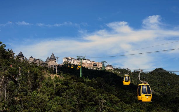Cable cars ascending to Sun World Ba Na Hills with castle-like structures in Da Nang.
