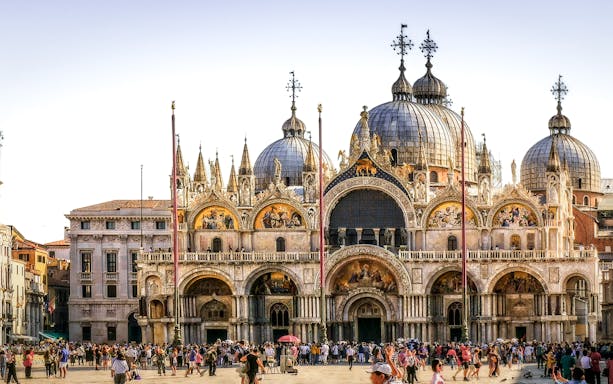 St. Mark's Basilica in Venice with tourists in the foreground.