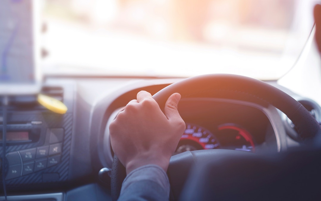 Driver steering a car during a private airport transfer in Bangkok.