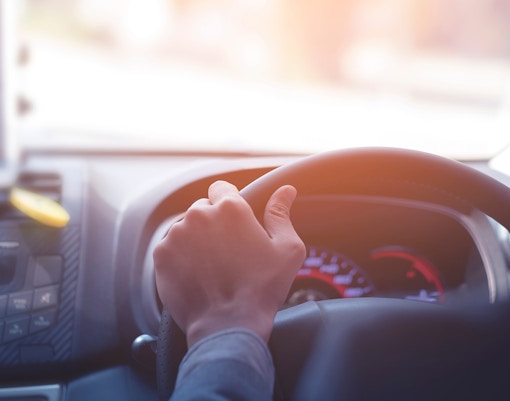 Driver steering a car during a private airport transfer in Bangkok.