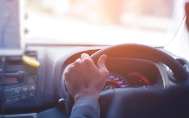 Driver steering a car during a private airport transfer in Bangkok.