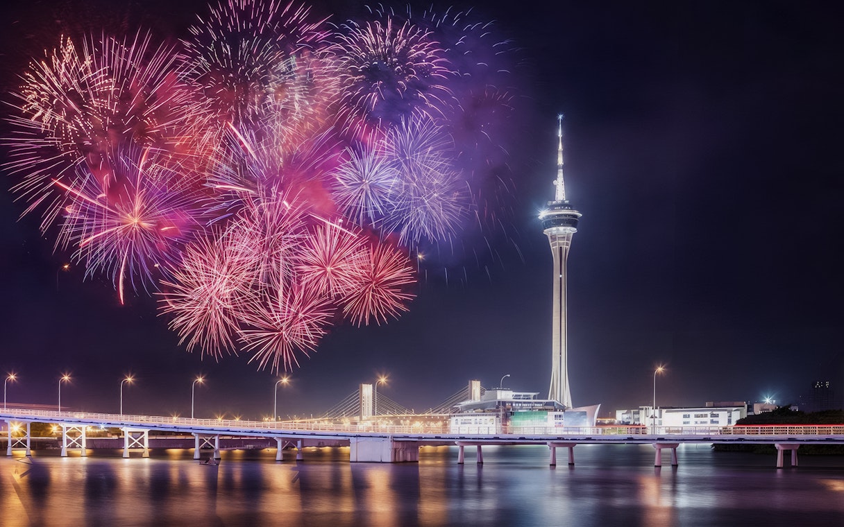 Fireworks over Hong Kong skyline viewed from TurboJET Ferry, featuring iconic tower and bridge.