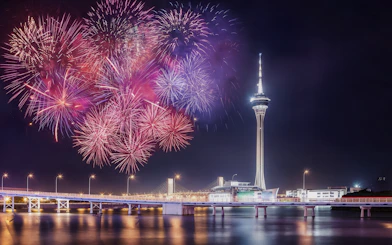 Fireworks over Hong Kong skyline viewed from TurboJET Ferry, featuring iconic tower and bridge.