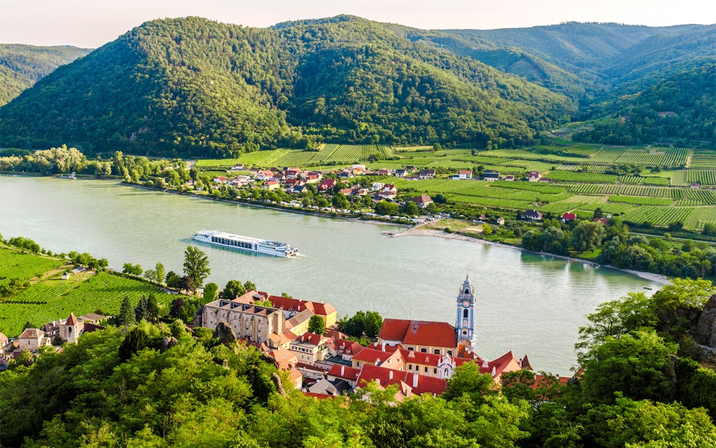 Dürnstein town on the Danube River with vineyards and hills in Wachau, Lower Austria.