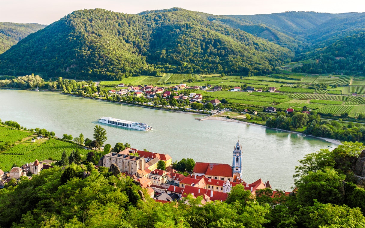 Dürnstein town on the Danube River with vineyards and hills in Wachau, Lower Austria.