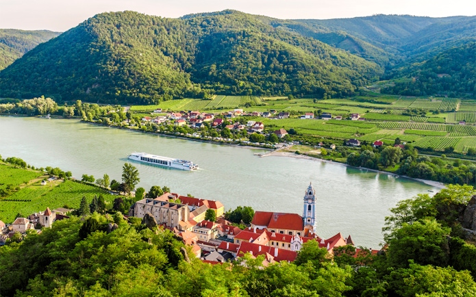 Dürnstein town on the Danube River with vineyards and hills in Wachau, Lower Austria.