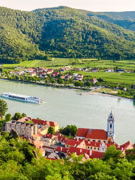 Dürnstein town on the Danube River with vineyards and hills in Wachau, Lower Austria.