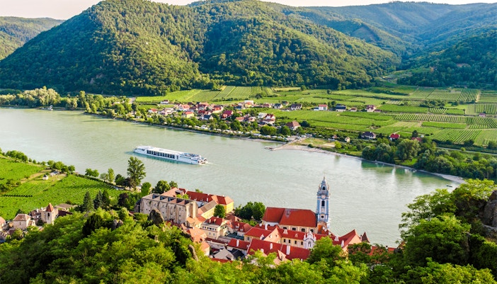 Dürnstein town on the Danube River with vineyards and hills in Wachau, Lower Austria.
