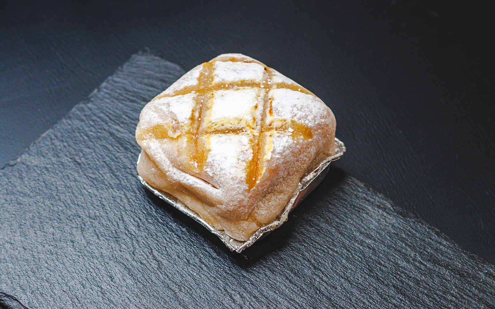 El ponche segoviano dessert on a slate plate, topped with powdered sugar.