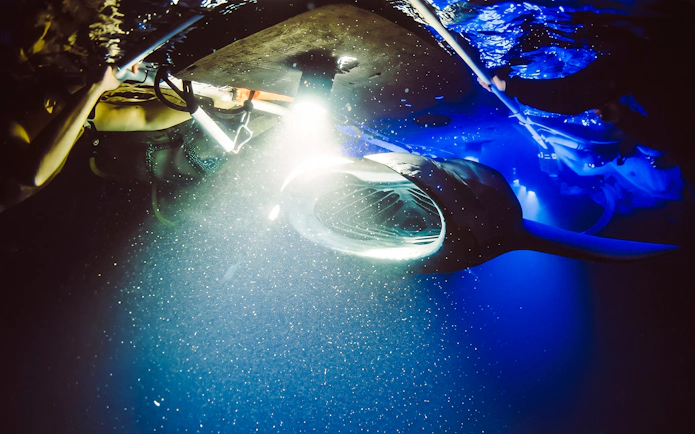 Snorkelers observe a manta ray illuminated underwater during a Kona night tour.