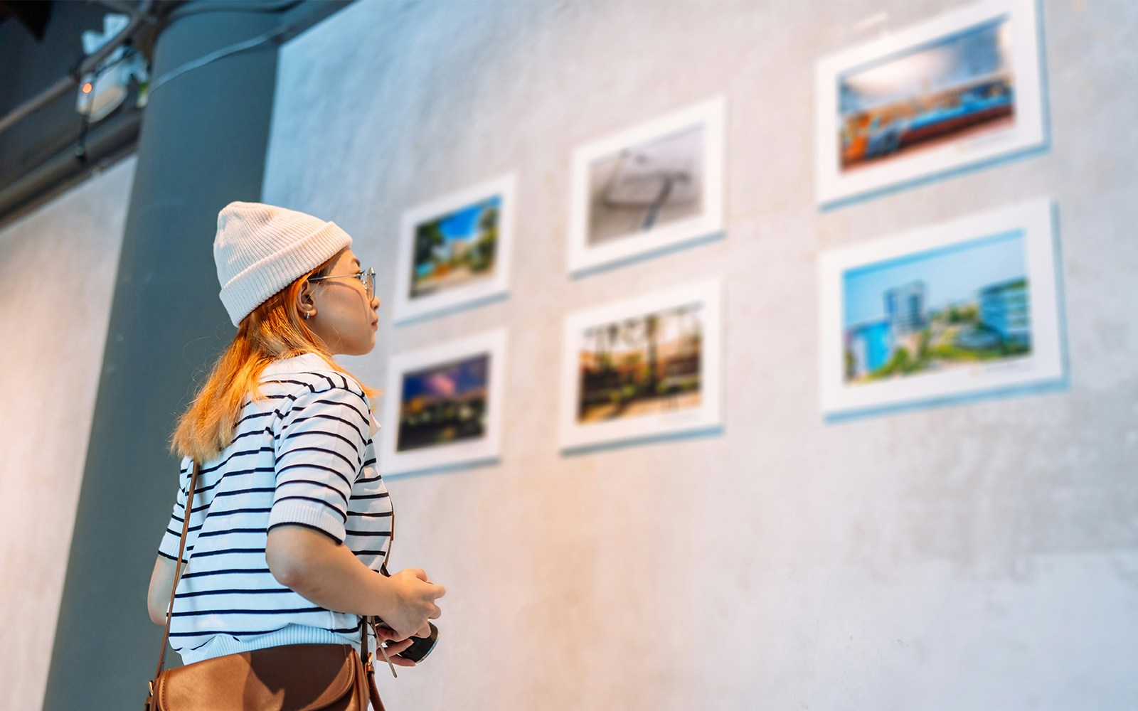 Woman in striped shirt viewing framed photos in an art gallery.
