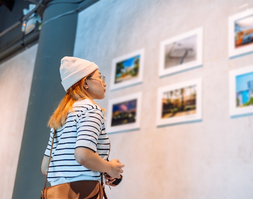 Woman in striped shirt viewing framed photos in an art gallery.