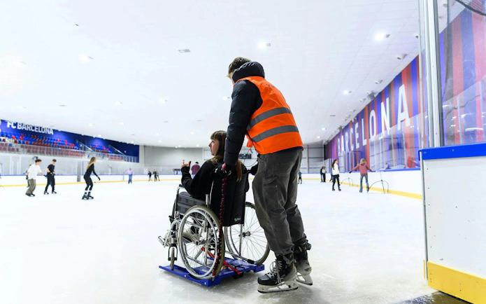 Wheelchair user on FC Barcelona Ice Rink assisted by staff.