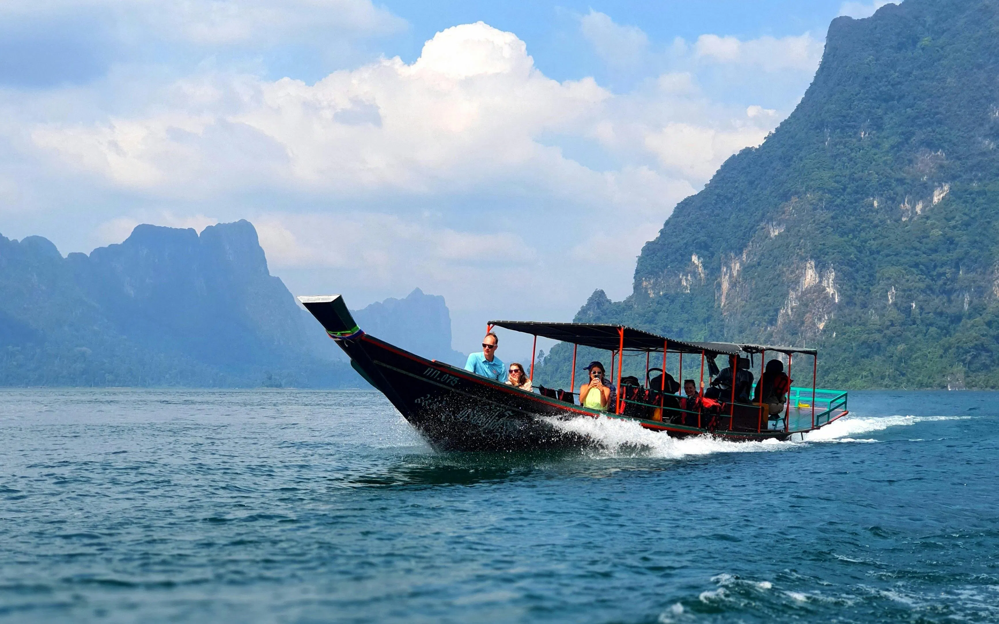 Boat tour on Cheow Lan Lake with limestone cliffs in Krabi, Thailand.
