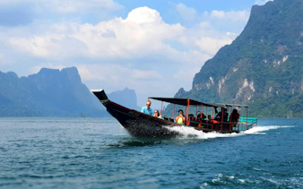 Boat tour on Cheow Lan Lake with limestone cliffs in Krabi, Thailand.
