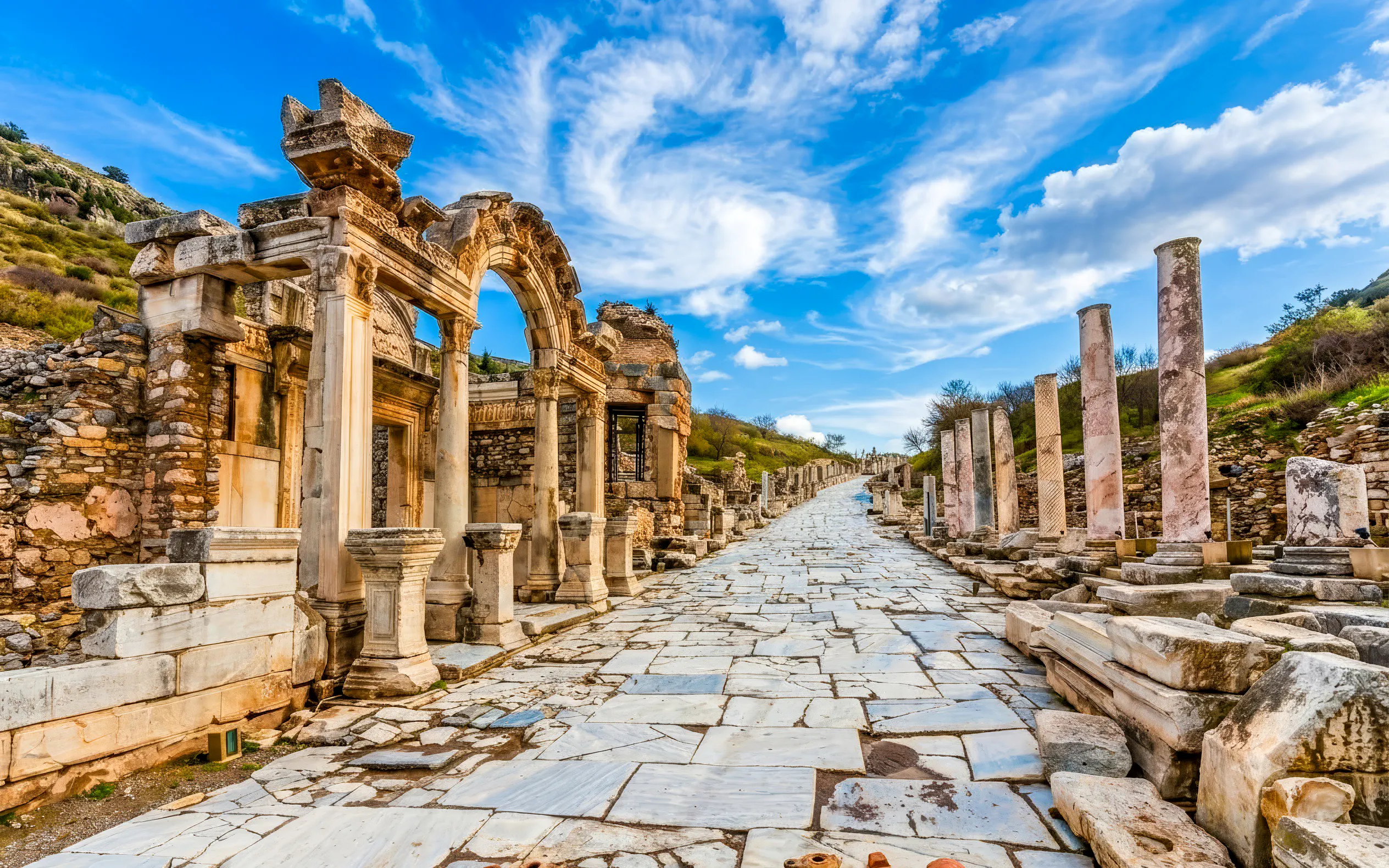 Ancient marble street and ruins in Ephesus, Turkey, under a blue sky.