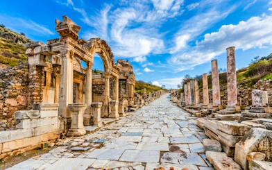 Ancient marble street and ruins in Ephesus, Turkey, under a blue sky.