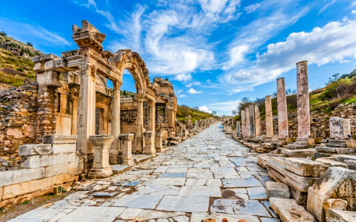 Ancient marble street and ruins in Ephesus, Turkey, under a blue sky.