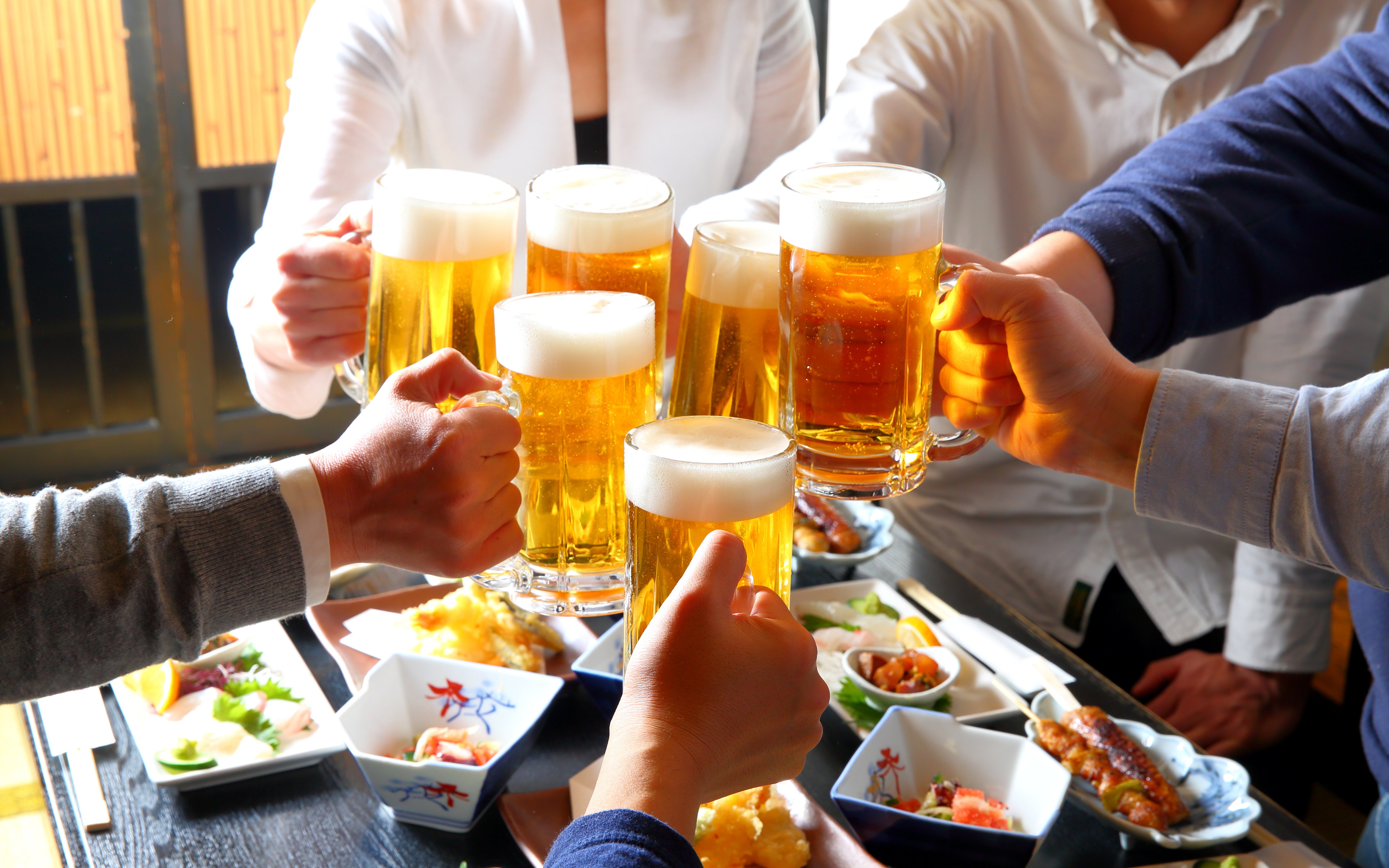 Guests toasting with beer at Shinjuku bar during Tokyo Izakaya Crawl Tour.
