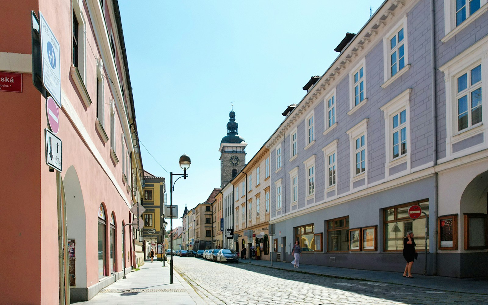 Street view in Ceske Budejovice with historic buildings and a clock tower.