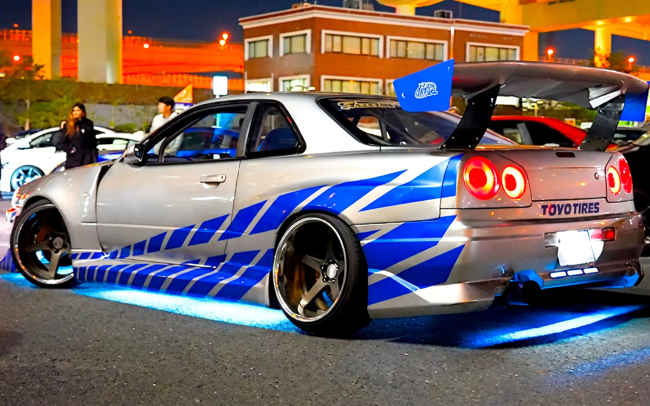 Sports car with blue racing stripes at night, part of Tokyo Drift 5.0 Fast & Furious Experience.