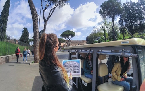 Tour guide pointing at Colosseum during Rome golf cart tour.