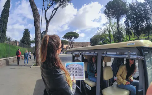 Tour guide pointing at Colosseum during Rome golf cart tour.