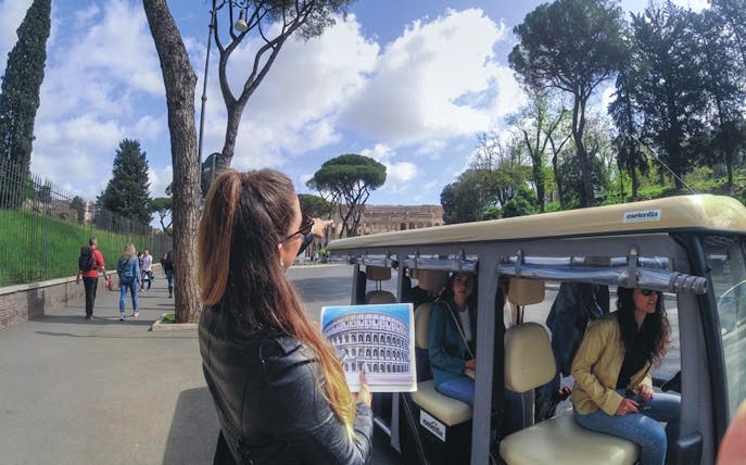 Tour guide pointing at Colosseum during Rome golf cart tour.