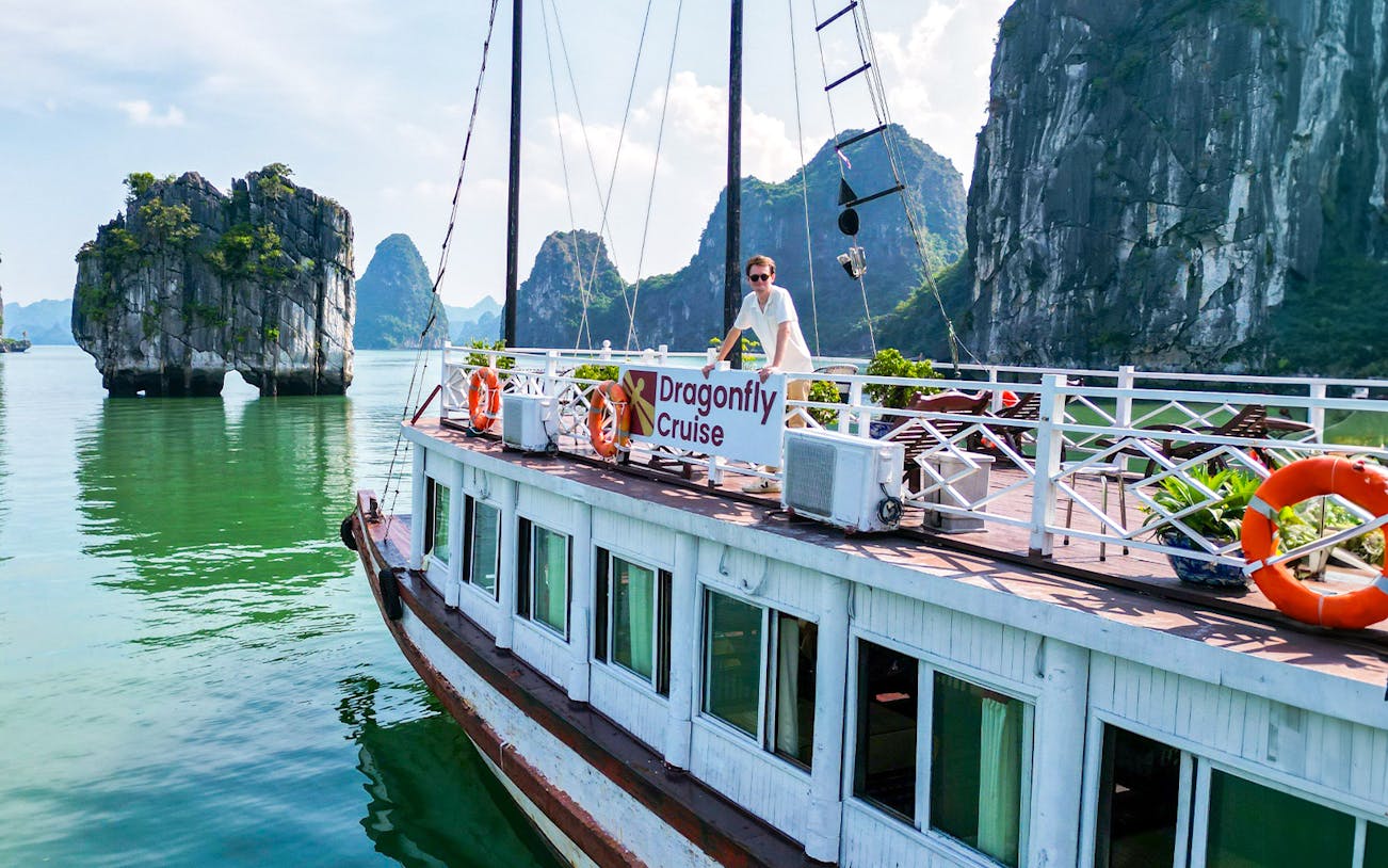 Dragonfly Cruise boat on Halong Bay with limestone karsts in the background.