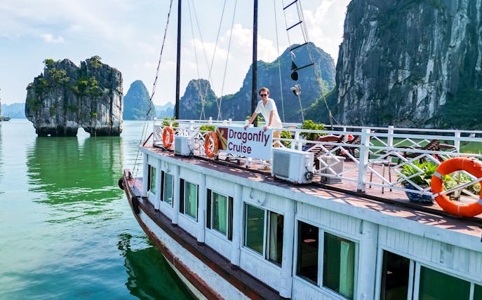 Dragonfly Cruise boat on Halong Bay with limestone karsts in the background.
