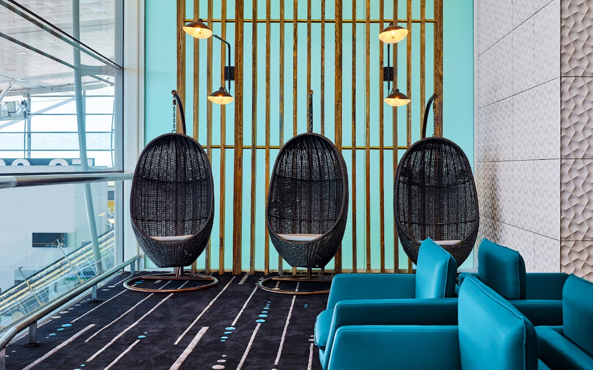 Hanging chairs and blue seating in Plaza Premium Lounge at an airport.