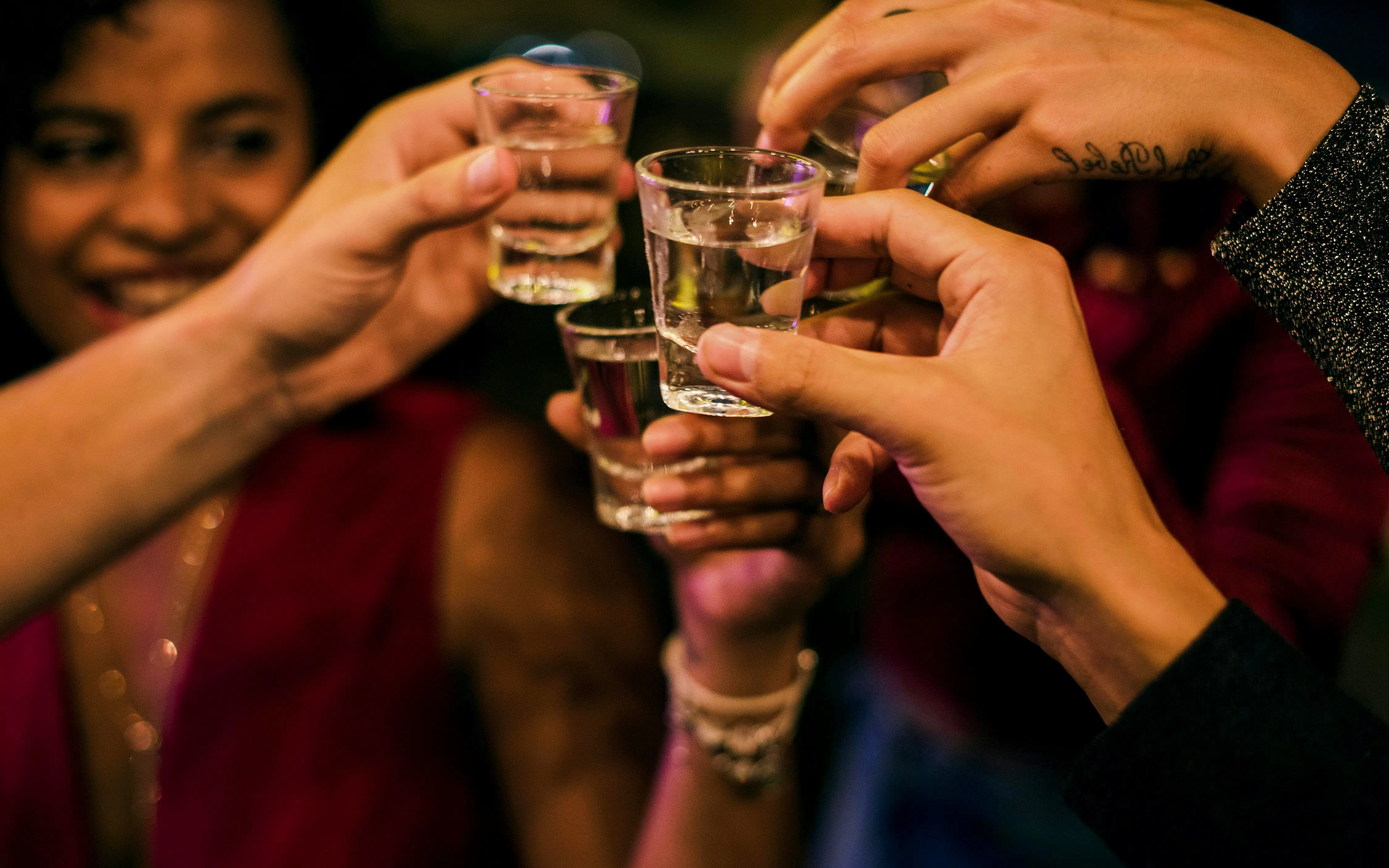 Friends toasting with shots during a night boat party.