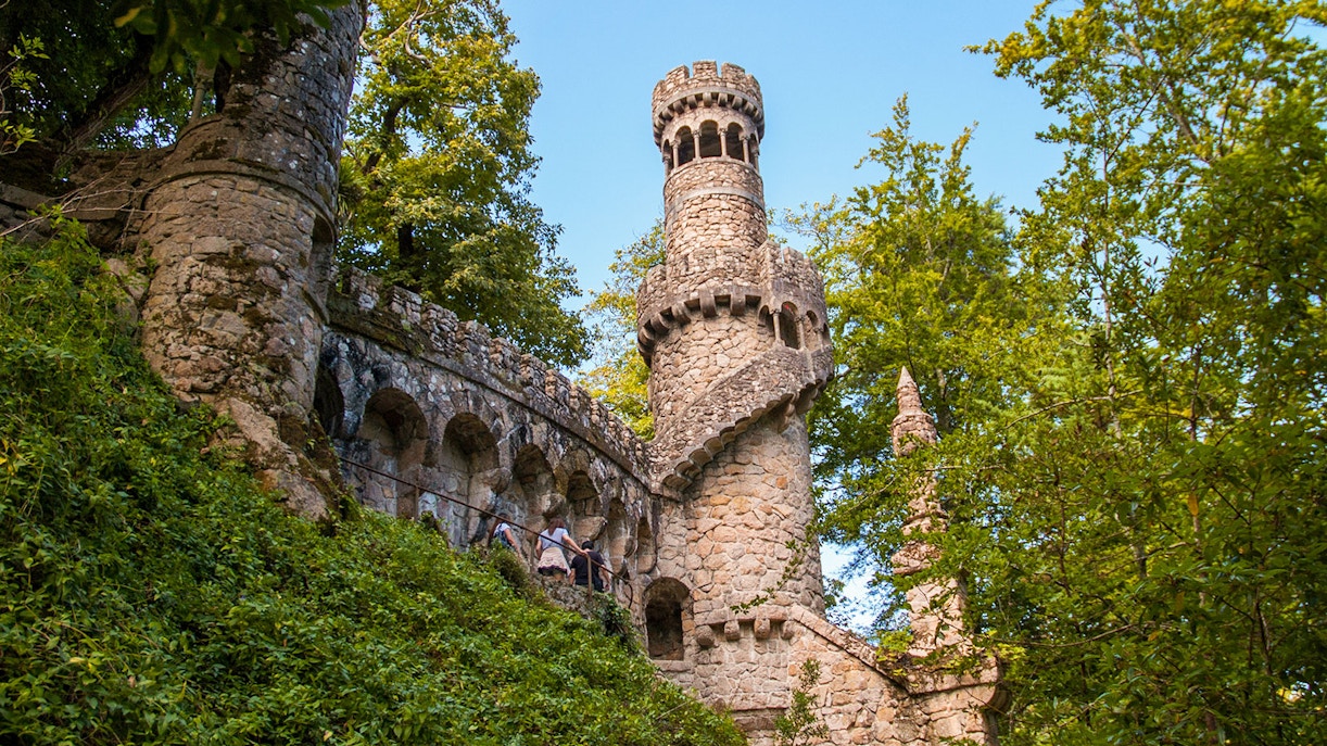 Quinta da Regaleira tower in Sintra, Portugal, surrounded by lush greenery.