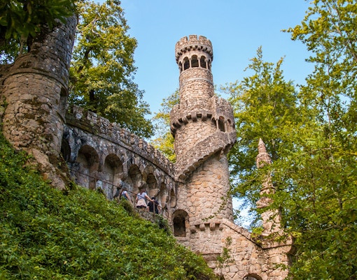 Quinta da Regaleira tower in Sintra, Portugal, surrounded by lush greenery.