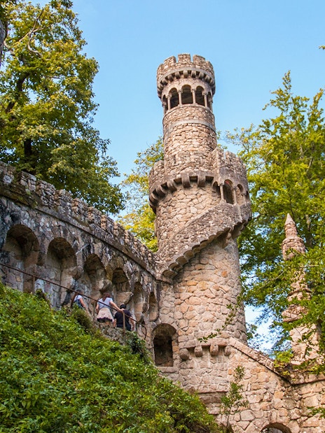 Quinta da Regaleira tower with spiral staircase in Sintra, Portugal, surrounded by lush greenery.