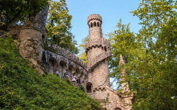 Quinta da Regaleira tower with spiral staircase in Sintra, Portugal, surrounded by lush greenery.