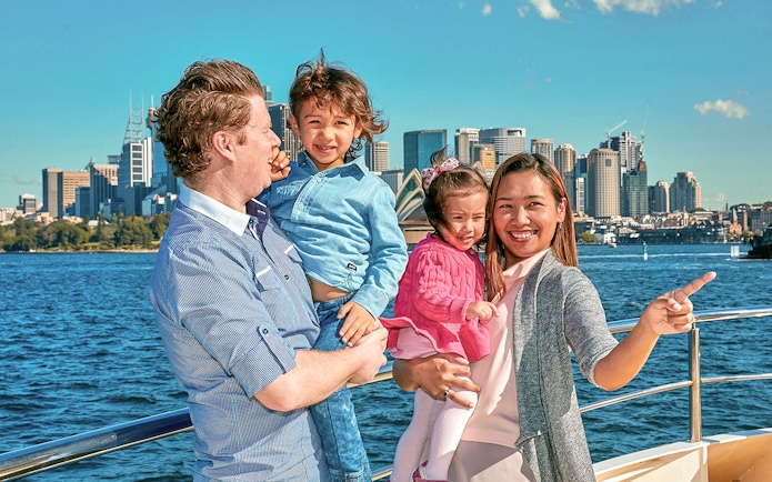 Family enjoying a cruise with Sydney Opera House and skyline in the background.
