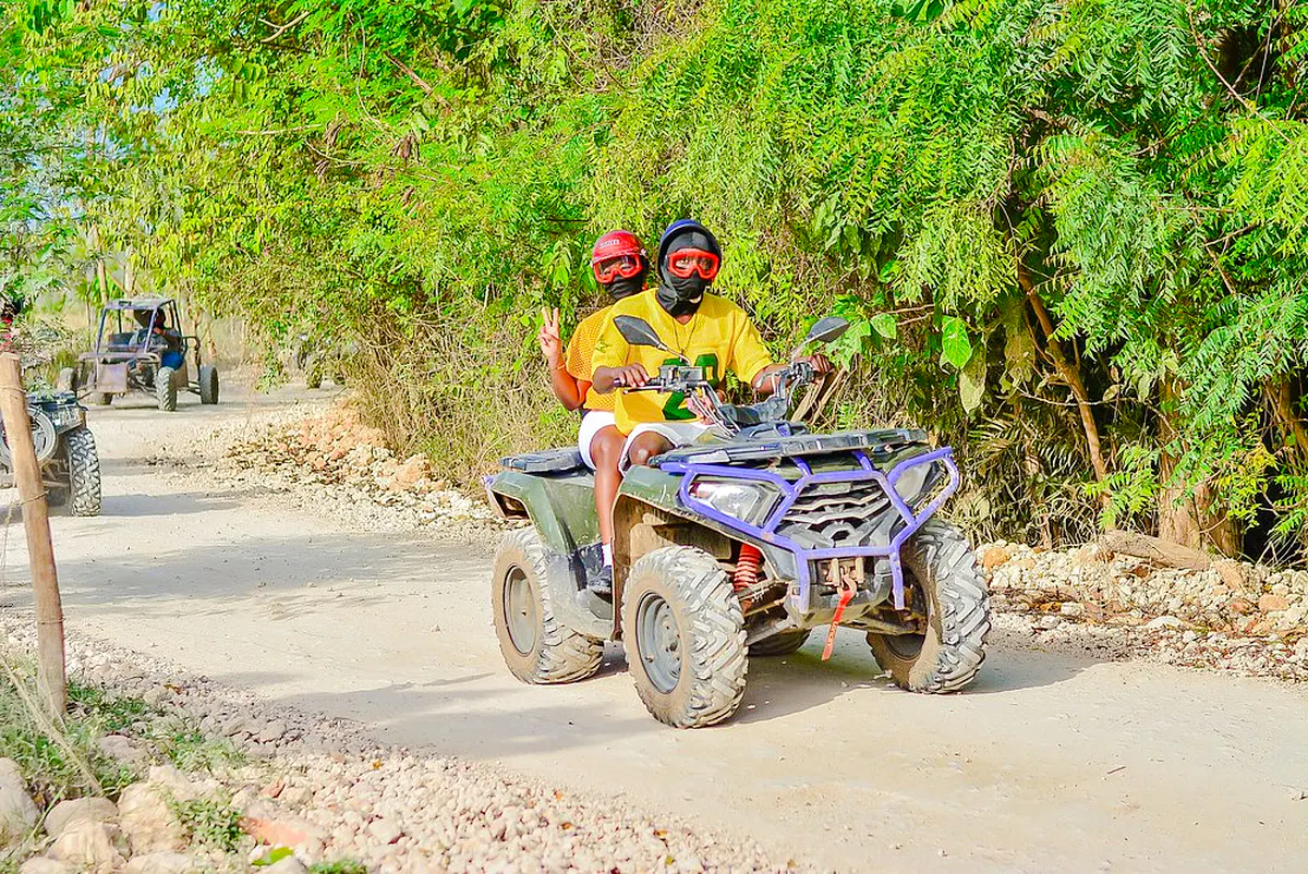 ATV riders on a dirt path surrounded by greenery in Punta Cana.