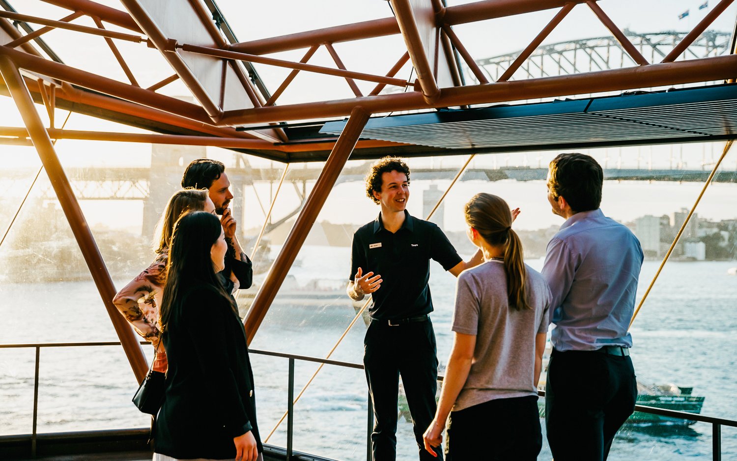 Group on a guided tour inside Sydney Opera House with Sydney Harbour Bridge view.